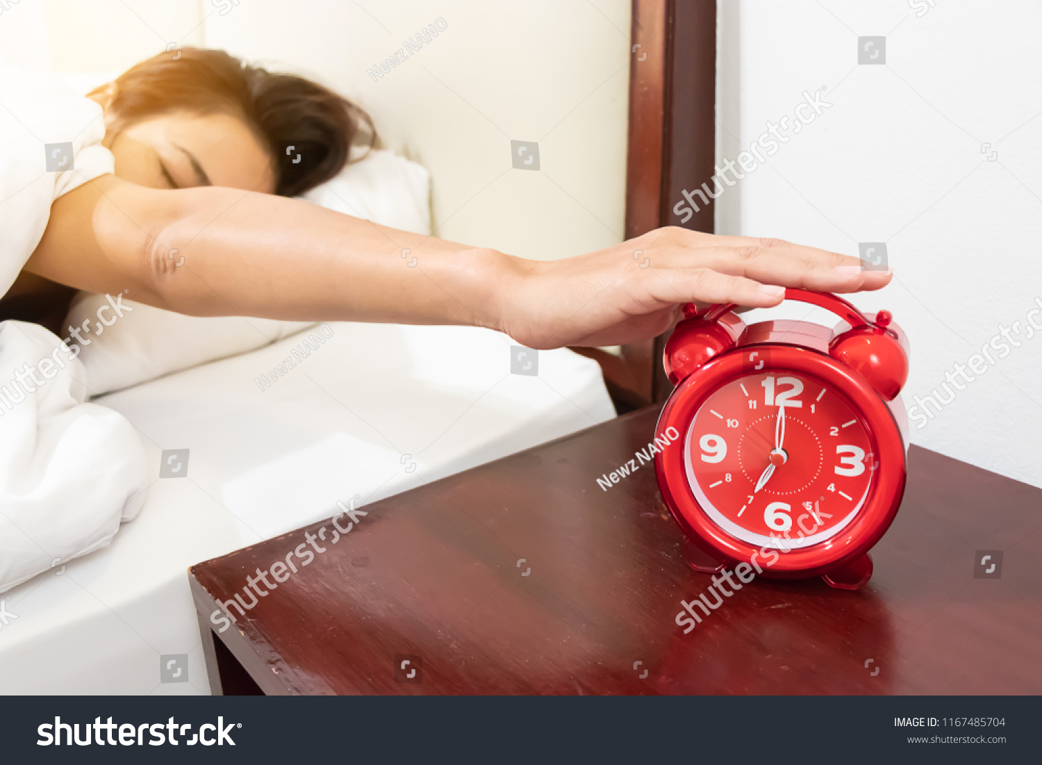 stock-photo-asian-girl-in-bed-reaching-out-to-pick-up-a-red-alarm-clock-on-the-table-wood-in-the-morning-1167485704.jpg
